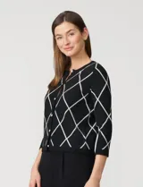 Cardigan tejido negro con estampado de rombos blancos, cuello redondo y cierre frontal con botones dorados. Marca Cable & Gauge.