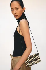 Mini bolso bandolera rectangular confeccionado con cuentas de madera multicolor en tonos beige, marrón y negro. Cuenta con una correa larga de cuentas y cierre superior de cremallera.