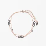 Pulsera de doble cadena en tono dorado con dijes en forma de símbolo de infinito y pequeños cubos decorativos.