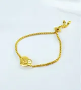 Pulsera de cadena tipo veneciana en tono dorado con sistema de cierre ajustable mediante deslizador. Presenta un dije en forma de corazón con la palabra LOVE grabada y un pequeño cristal incrustado.