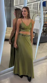 Conjunto de dos piezas color verde oliva, compuesto por un top corto con tirantes finos y escote en V cruzado, y una pollera larga de corte evasé con caída fluida.