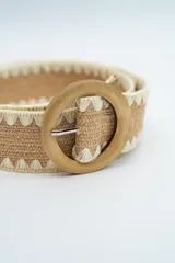 Cinturón de tejido elástico en color negro con bordes en color crema y hebilla circular de madera.