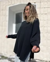 Sweater de punto color negro, con diseño oversize, cuello redondo, costura central vertical y aberturas laterales en el ruedo. Presenta mangas largas con puños acanalados.