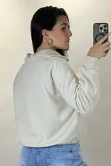 Buzo deportivo color blanco con cuello polo y cierre frontal parcial. Presenta mangas largas con puños elásticos y ruedo ajustable con cordón elástico.