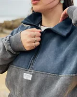 Buzo oversize de color gris oscuro con efecto stone wash, cuello alto con medio cierre y bolsillo frontal tipo canguro.