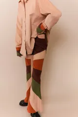Pantalón acampanado de pana color beige con parches de pana marrón, verde y naranja.