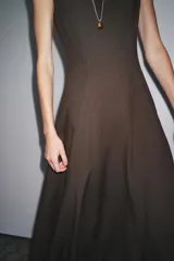 Vestido midi marrón sin mangas confeccionado en hilatura con 10% de lino. Tiene cuello redondo, corte evasé y cierre trasero con cremallera oculta.