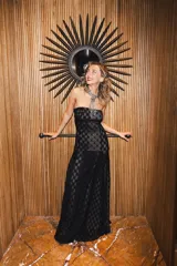 Vestido largo strapless de encaje negro con transparencias y espalda descubierta con tiras cruzadas, de corte entallado y falda de caída suelta.