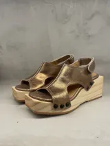 Sandalias de cuero color bronce con plataforma de madera y detalles de tachas negras.