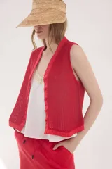 Chaleco rojo de tejido calado con detalles en lino, silueta sofisticada y botones forrados del mismo material.
