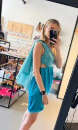 Vestido corto turquesa de un hombro con volado de gasa y corte en la cintura.