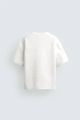 Sudadera de corte relajado confeccionada en tejido técnico interlock con mezcla de algodón, cuello redondo y manga corta.