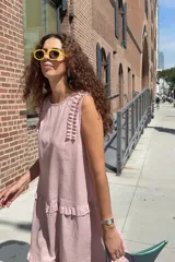 Vestido midi rosado con diseño sin mangas, cuello redondo y detalles de volados en los hombros y en el ruedo.