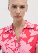 Vestido midi de corte recto con estampado floral en tonos fucsia y rosado. Presenta cuello camisero, cierre frontal de botones, mangas cortas y cinturón ajustable de la misma tela para entallar la cintura.