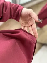 Conjunto de dos piezas color bordó, compuesto por un buzo de cuello redondo con mangas largas y un pantalón de corte holgado con cintura elástica.