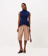 Blusa azul marino sin mangas de la marca Cortelle, con cuello alto, recortes estructurales y dobladillo estilo peplum asimétrico.