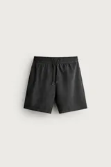 Bañador largo para hombre confeccionado en tejido técnico de color negro, con cintura elástica ajustable mediante cordón, bolsillos laterales y forro interior.