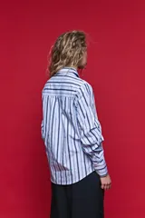 Camisa de algodón celeste con rayas verticales azul marino y marrón, cuello camisero clásico y cierre frontal de botones nacarados.