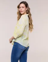 Blusa celeste con estampado efecto pincelada blanca, de corte semi holgado, escote en V con cuello solapa y media abotonadura frontal con botones nacarados. Presenta finas alforzas verticales en la pechera y mangas 3/4 con puños elastizados.
