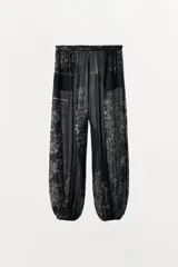 Pantalón bombacho de tiro medio, confeccionado en tejido semitransparente de viscosa con estampado floral. Presenta cintura elástica, bolsillos laterales y bajo abullonado con acabado elástico.