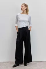Pantalón de vestir negro con rayas verticales blancas, de corte recto y tiro alto.