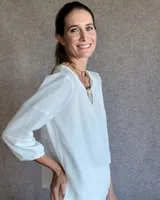 Blusa de mangas tres cuartos con diseño de corte recto y cuello redondo. Presenta costuras horizontales decorativas en las mangas y un acabado liso.