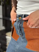 Falda midi de denim con elastano, corte recto y tajo frontal. Presenta bolsillos delanteros de cuero en color tostado y diseño clásico.