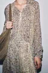 Vestido largo con estampado floral multicolor, cuello redondo con lazo ajustable, mangas largas abullonadas con puños elásticos y forro interior.