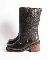 Bota de cuero negra con caña media, punta cuadrada, taco bloque y arnés con hebillas y tachas plateadas.