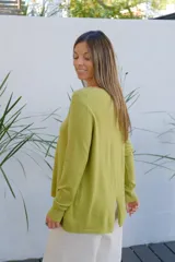 Sweater de punto color verde oliva, con cuello redondo, manga larga y corte holgado con ruedo asimétrico.