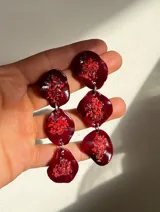 Aros colgantes con tres piezas de forma irregular color borgoña con incrustaciones de piedras rojas.