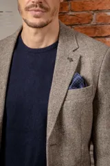 Chaquetón de corte slim fit confeccionado en una mezcla de seda y lana, color gris con textura jaspeada. Presenta solapas clásicas, cierre frontal de botones y bolsillo en el pecho con pañuelo decorativo.