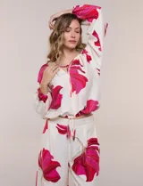 Conjunto de dos piezas de crep compuesto por una blusa holgada con escote en V y mangas largas abullonadas, y un pantalón palazzo tiro alto con pretina elástica. Presenta un estampado floral en tonos rosados sobre base blanca.
