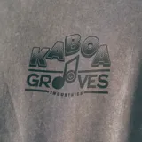 Remera gris de corte oversize con estampa en la espalda de un disco de vinilo sostenido por dos manos.