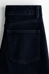 Jean de tiro alto y pierna ancha en denim de algodón negro, con diseño clásico de cinco bolsillos, cierre de cremallera y botón metálico.