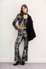 Saco corto de terciopelo negro con estampado floral plateado, cuello cuadrado, mangas largas y aberturas en la zona del abdomen.