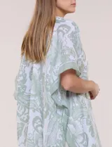 Kimono de gasa ligera con estampado floral en tonos de azul y blanco, silueta amplia, mangas cortas y detalle de borlas en el ruedo asimétrico.