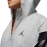 Campera rompevientos con capucha Nike Jordan, diseño color block en tonos gris claro, gris oscuro y negro. Presenta cierre frontal completo, bolsillos laterales y logo Jumpman bordado en el pecho.