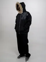 Campera de algodón y poliéster color negro con cierre frontal y capucha con borde de piel sintética. Cuenta con bolsillos frontales estilo canguro y diseño estampado en el pecho.