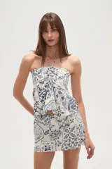 Top strapless de viscosa con estampado de azulejos en tonos azul y blanco. Presenta un diseño con cuello halter, detalle de fruncido central y un lazo decorativo en el frente.