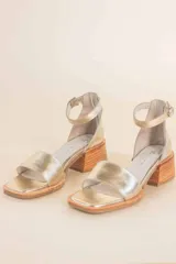 Sandalias doradas de cuero con pulsera al tobillo y taco de madera.