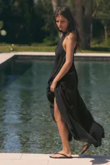 Vestido midi de corte fluido y diseño minimalista, con cuello redondo y mangas sisa. Presenta un cierre en la espalda con abertura y lazada ajustable.