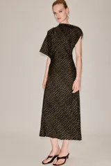 Vestido midi de corte asimétrico con escote barco, una manga corta y un hombro descubierto. Presenta un diseño drapeado en el lateral y estampado de lunares dorados sobre fondo negro.