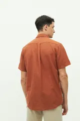 Camisa de manga corta confeccionada en una mezcla de lino y algodón, con cuello clásico, cierre frontal de botones y bolsillo en el pecho con logo bordado.