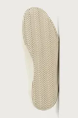 Zapatilla casual sin cordones de tipo slip-on, confeccionada en cuero con acabado de serraje y tejido en color beige. Cuenta con elásticos laterales en el empeine y suela de goma a tono.