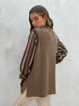 Sweater de lana color crudo con mangas largas abullonadas en gris y blanco, con diseño de rayas y perforaciones. Cuello redondo y puños acanalados.