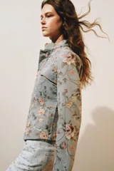 Blazer de jacquard de algodón con estampado floreado, cuello subido, manga larga y cierre frontal con botones. Presenta bolsillos de plastrón en el delantero, detalle de aplicación de lentejuelas, forro interior a tono y bajo asimétrico.