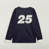 Camiseta Adidas de manga larga en colaboración con la banda Oasis, de color negro con cuello polo, puños y detalles en blanco marfil. Presenta las tres tiras características en las mangas, el logo trébol de Adidas, un escudo circular conmemorativo de la gira 'Live '25' y el estampado con la inscripción 'oasis' en el centro del pecho.
