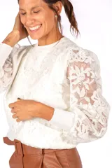 Sweater blanco de encaje con diseño floral, cuello redondo y mangas largas abullonadas con puños tejidos.