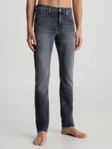 Pantalón de jean gris oscuro de corte slim, con cintura media, cinco bolsillos y cierre con cremallera.